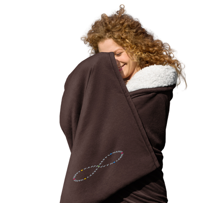 Happy young woman wrapped in soft brown sherpa throw blanket with a happy embroidered infinity symbol HappyStuff