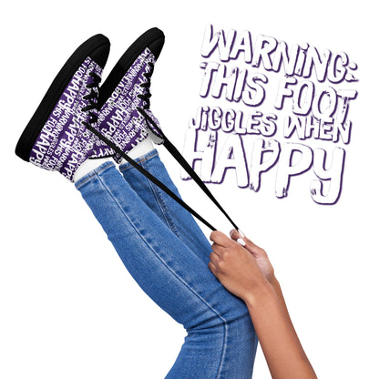 Womens feet in the air holding laces of HappyStuff purple and white high tops fun print Warning This Foot Jiggles When Happy black sole