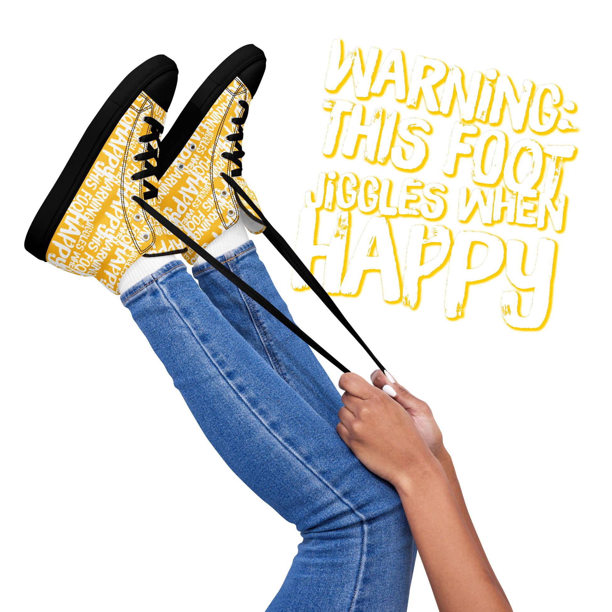 Womens feet in the air holding laces of HappyStuff yellow and white high tops fun print Warning This Foot Jiggles When Happy black sole