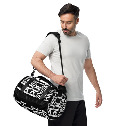 Man carrying gym bag adjustable removable padded shoulder strap HappyStuff Brand small duffle bag black and white all over print Lift Push Pull Sweat Repeat Happy