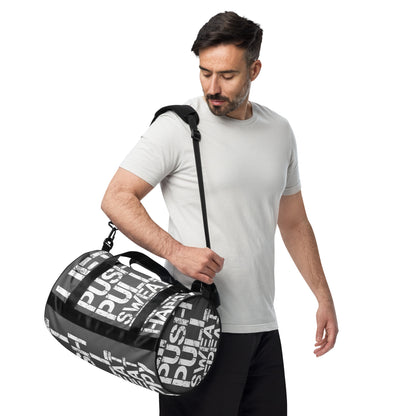 Man carrying gym bag adjustable removable padded shoulder strap HappyStuff Brand small duffle bag slate grey and white all over print Lift Push Pull Sweat Repeat Happy black detail