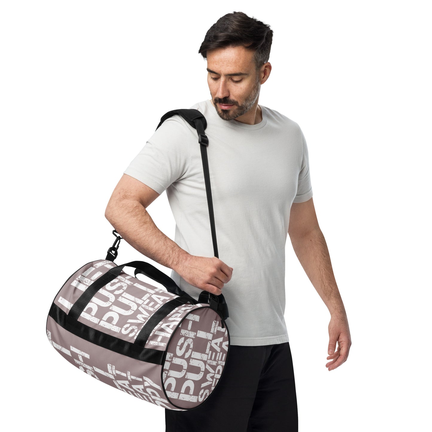 Man carrying gym bag adjustable removable padded shoulder strap HappyStuff Brand small duffle bag taupe and white all over print Lift Push Pull Sweat Repeat Happy black detail