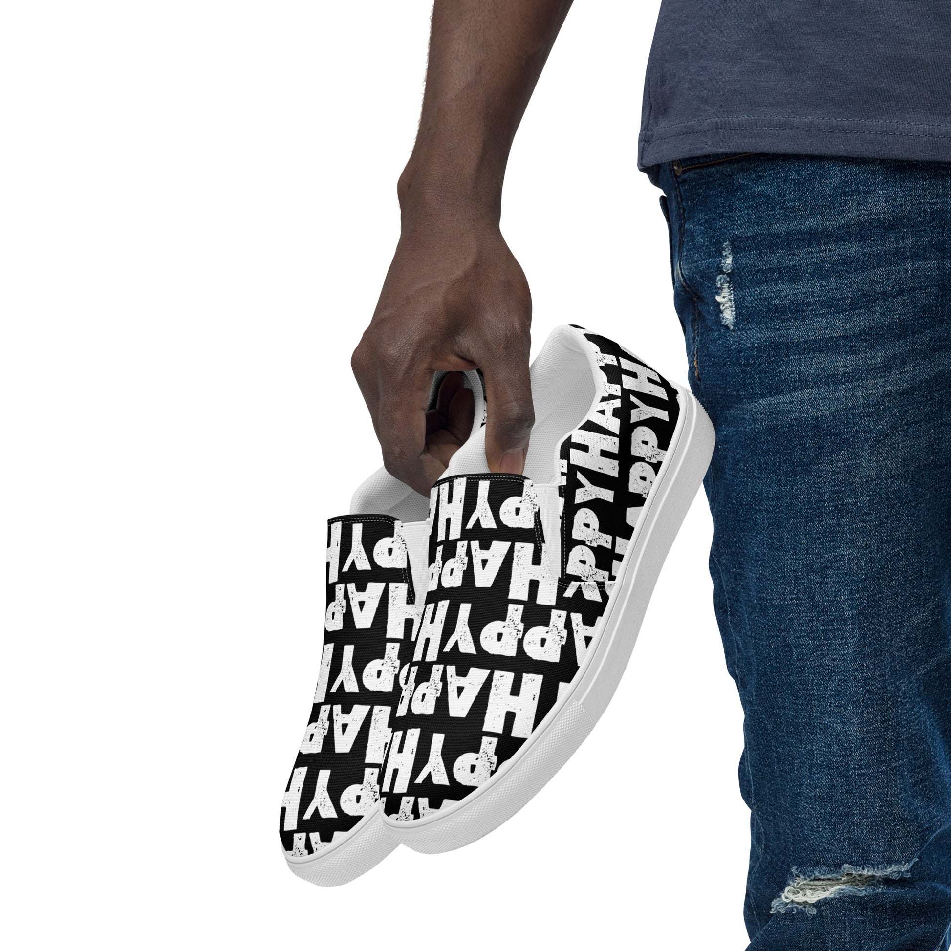 Mans hand holding happy shoes at his side fun black and white sneakers Happy Sponge Printed HappyStuff canvas slip on shoes