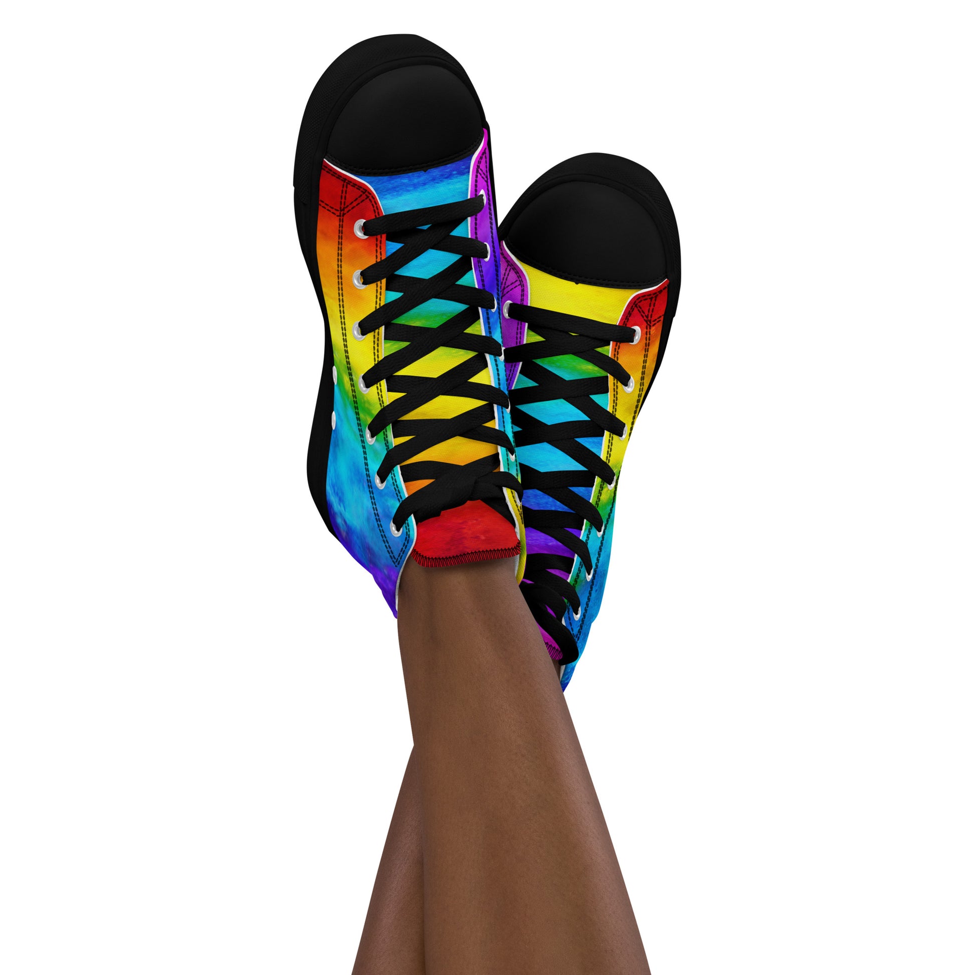 Feet in the air wearing womens sneakers ankles crossed sporting rainbow shoes holi colours printed on white high tops black sole