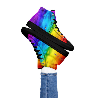 Womans right foot propping up rainbow shoes holi colours printed on white high top sneakers black sole balancing left sneaker atop