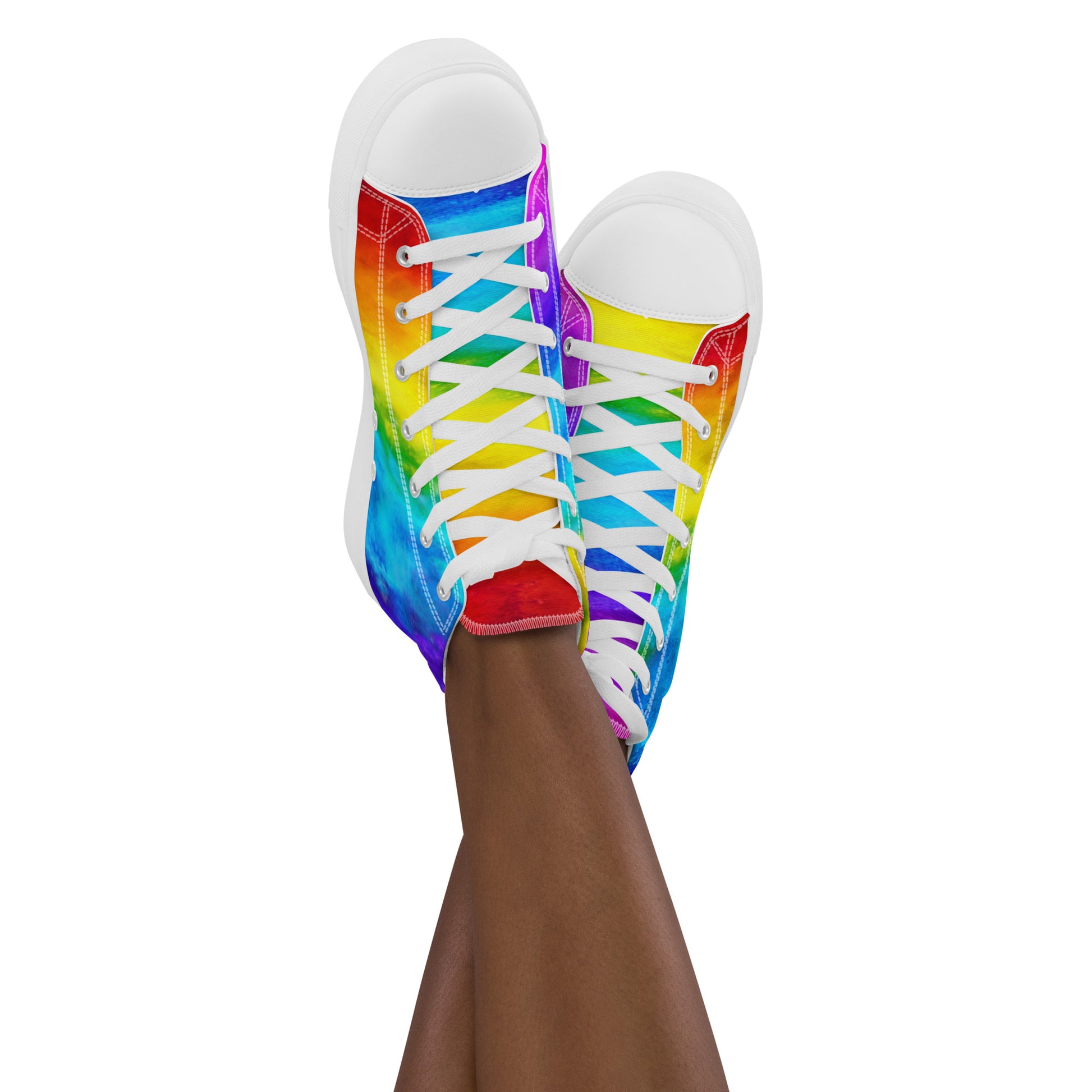 Feet in the air wearing womens sneakers ankles crossed sporting rainbow shoes holi colours printed on white high tops